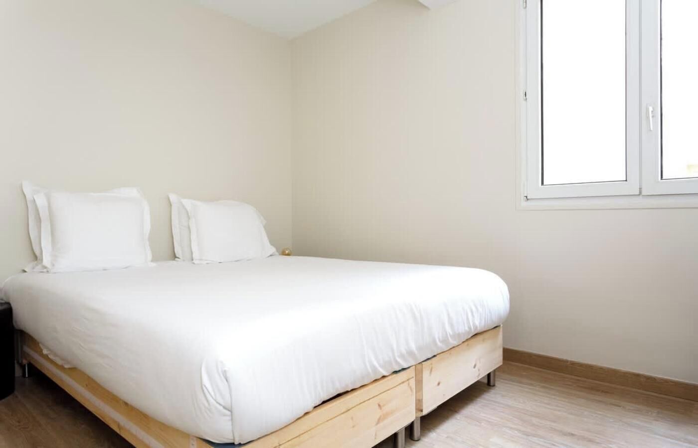 Ein Schlafzimmer mit einem Einzelbett, weißer Bettwäsche und einem Holzkopfende.