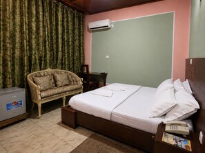 A bedroom with a bed, a chair, a desk, an air conditioner, and a telephone. - Hotel Residence Madadjeu (Yaoundé)