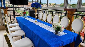 Un comedor con mantel azul, sillas blancas, un candelabro dorado y un ramo de flores.