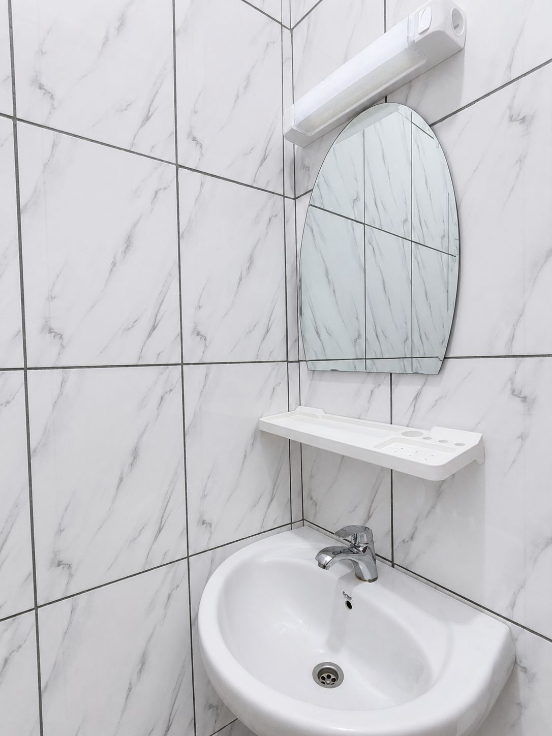 A bathroom with a white marble sink, a mirror, and a towel rack.