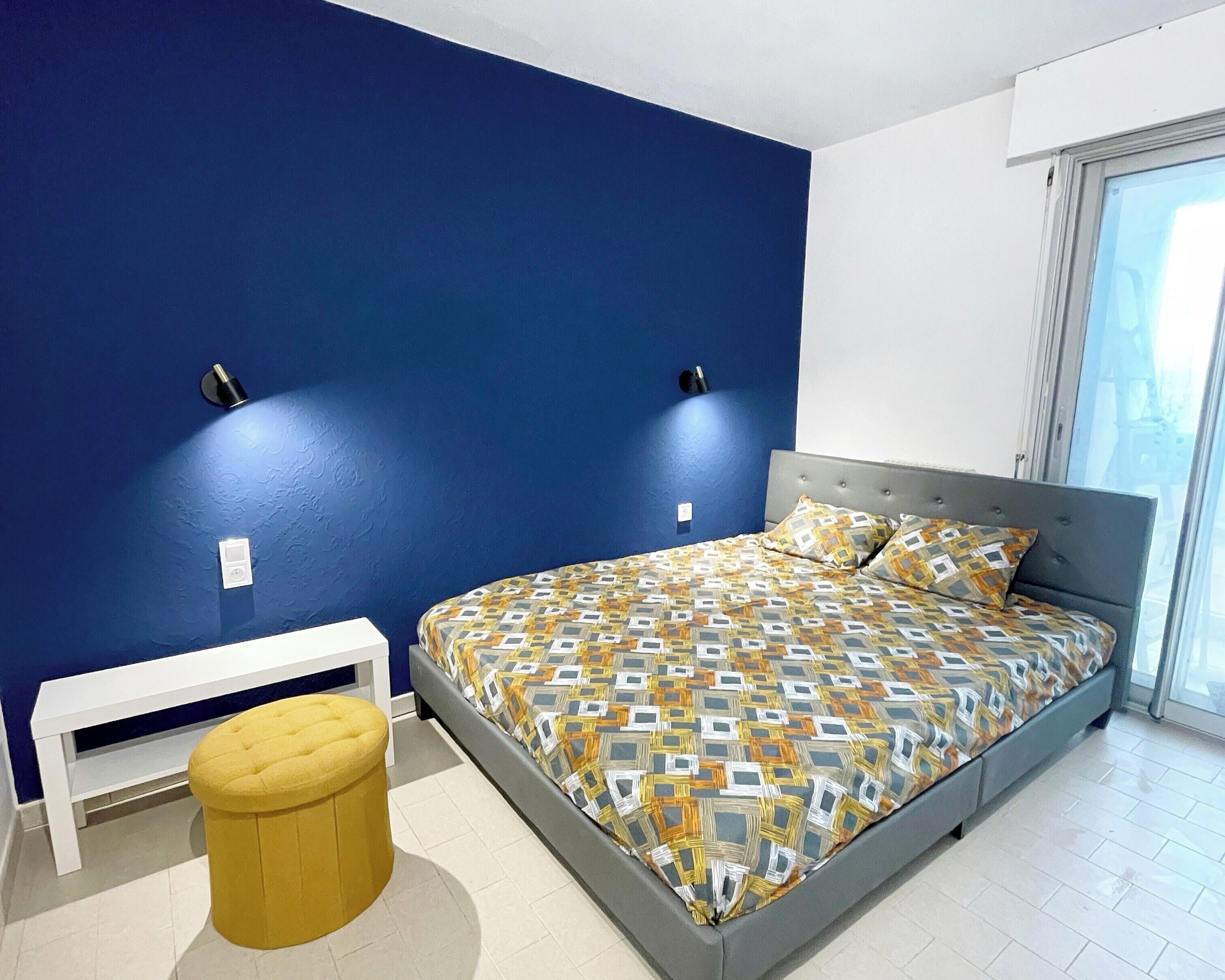 Een slaapkamer met een bed, een bankje en een raam.