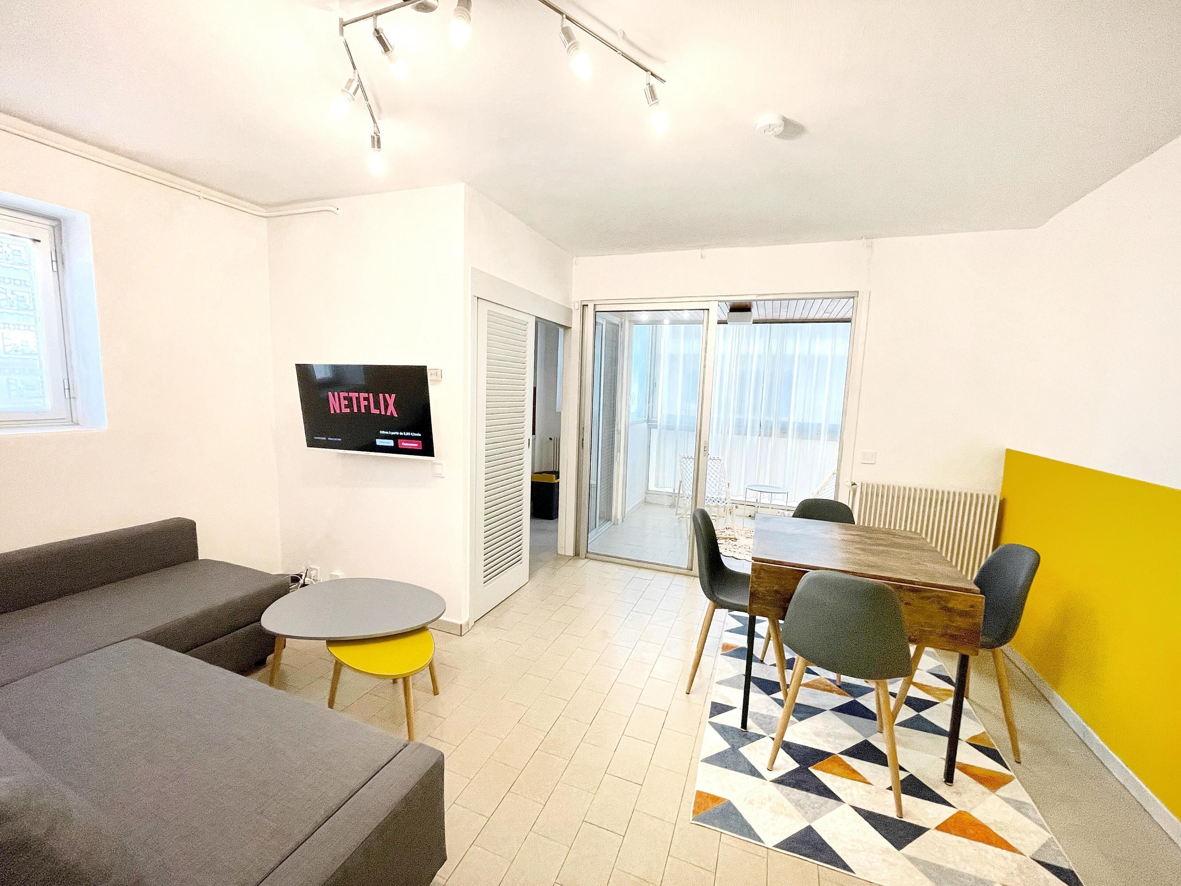 Un salon moderne avec un canapé, une petite table et un téléviseur fixé au mur.
