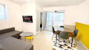 A modern living room with a sofa, a small table, and a TV mounted on the wall. - Apartment with balcony - sea view (Canet-en-Roussillon)