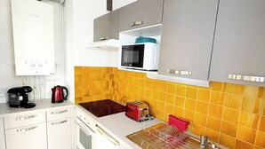 A compact kitchen with white cabinets, a microwave, a coffee maker, and a dish rack. - Apartment with balcony - sea view (Canet-en-Roussillon)