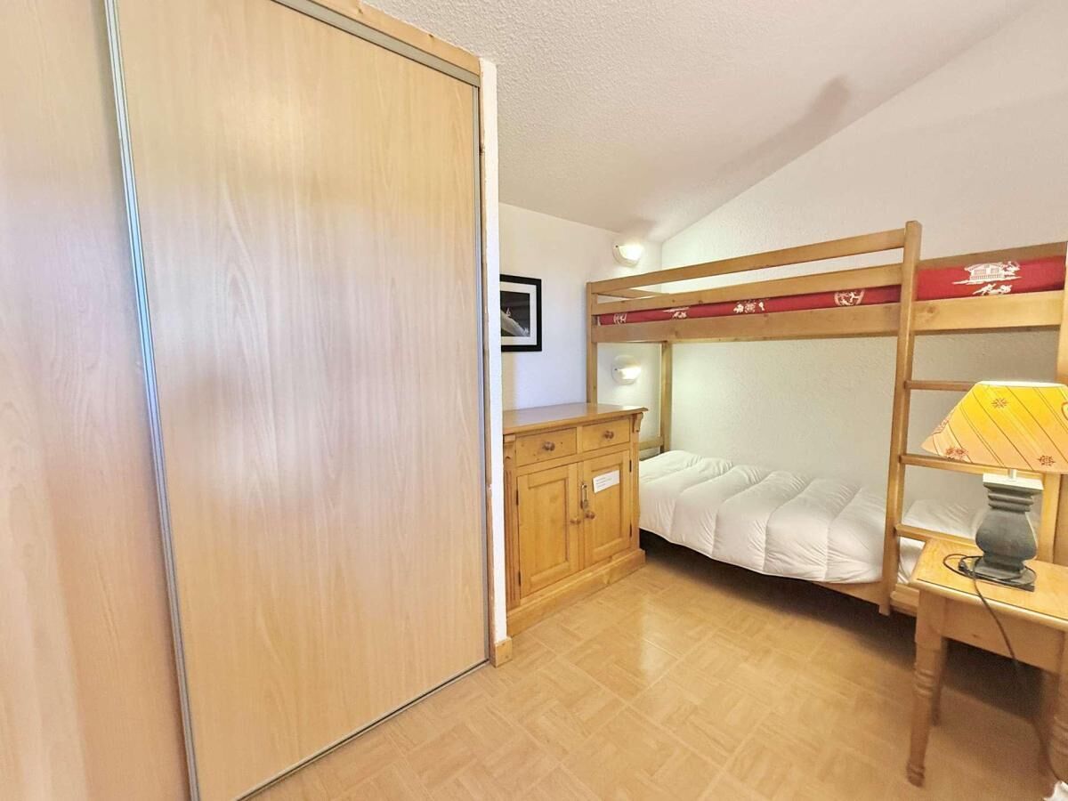 Une chambre avec un lit superposé, une armoire en bois et un bureau avec une lampe.