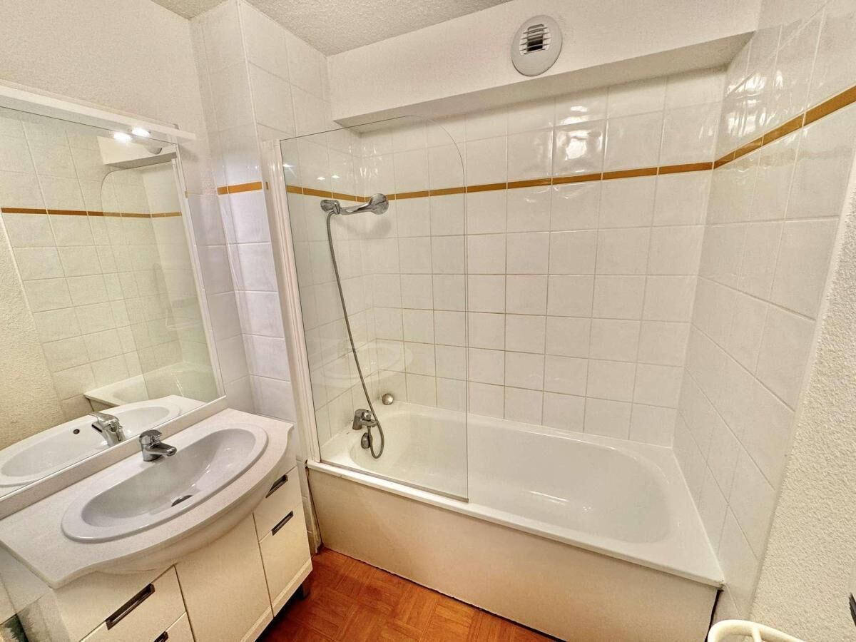 A bathroom with a white sink, mirror, and bathtub.
