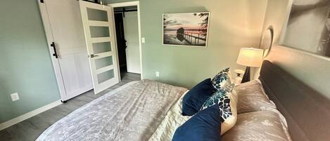 Une chambre à coucher avec un lit, un ventilateur de plafond, une table de chevet avec une lampe et un tableau au mur.