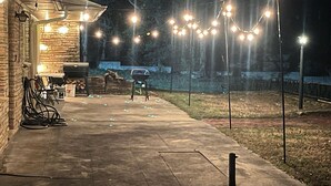 A patio area with a barbecue grill, outdoor seating, and string lights. - Sunset Drive! (Wewoka)