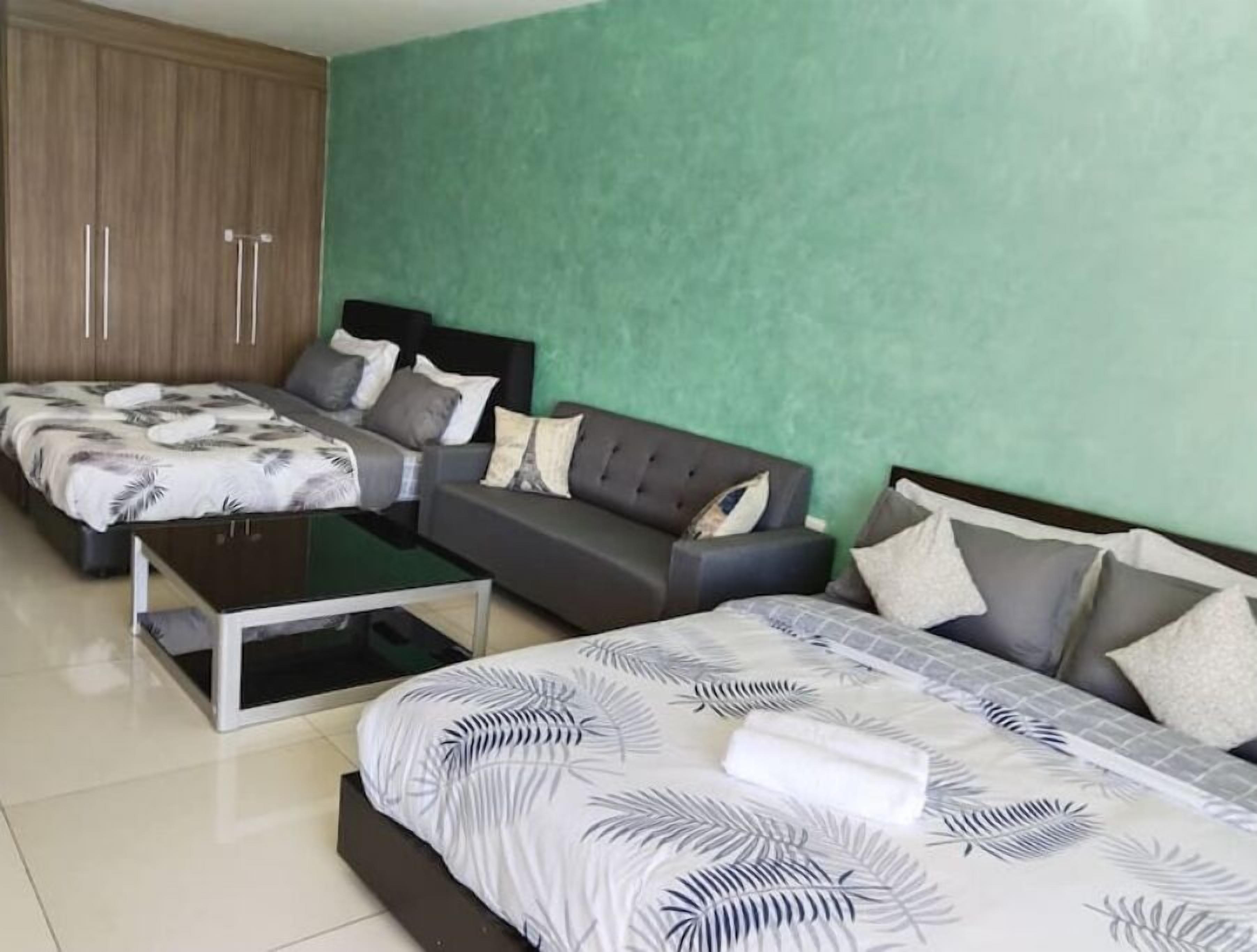 Quarto com duas camas, um sofá e uma mesa de centro.