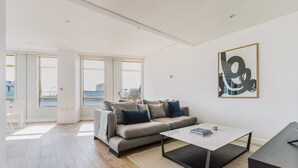 Ein modernes Wohnzimmer mit einem grauen Sofa, einem Couchtisch und einem großen abstrakten Gemälde an der Wand.