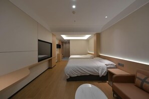 Ett modernt hotellrum med en stor säng, en soffa, en TV och ett skrivbord.