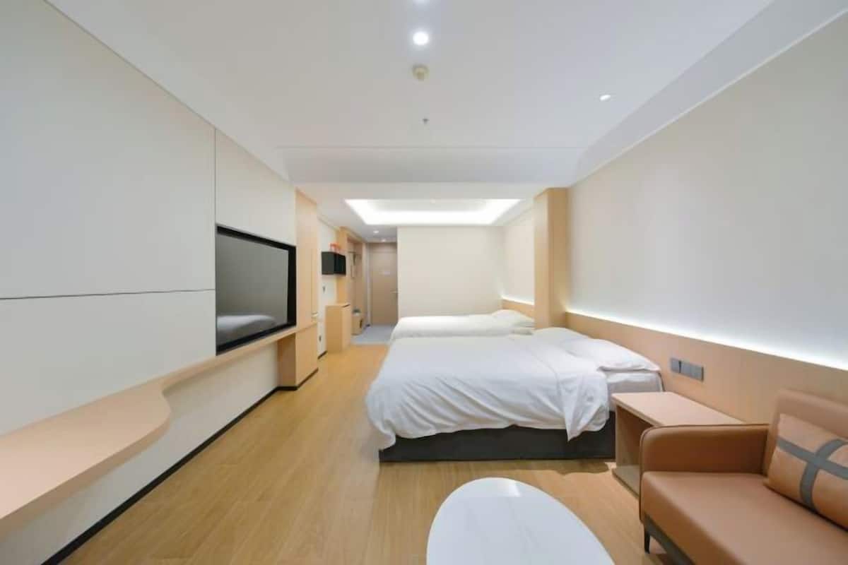 A modern hotel room with a large bed, a sofa, a TV, and a desk.