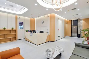 A reception area with a reception desk, seating area, and a digital display. - Tianhe Express Hotel (Shenyang Middle Street Forbidden City) (Shenyang)