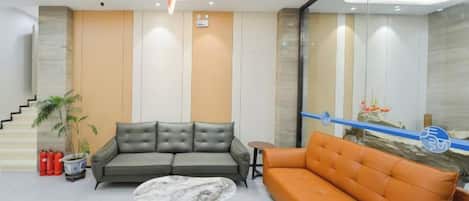 A modern lobby with a sofa, a coffee table, a staircase, and a decorative wall.