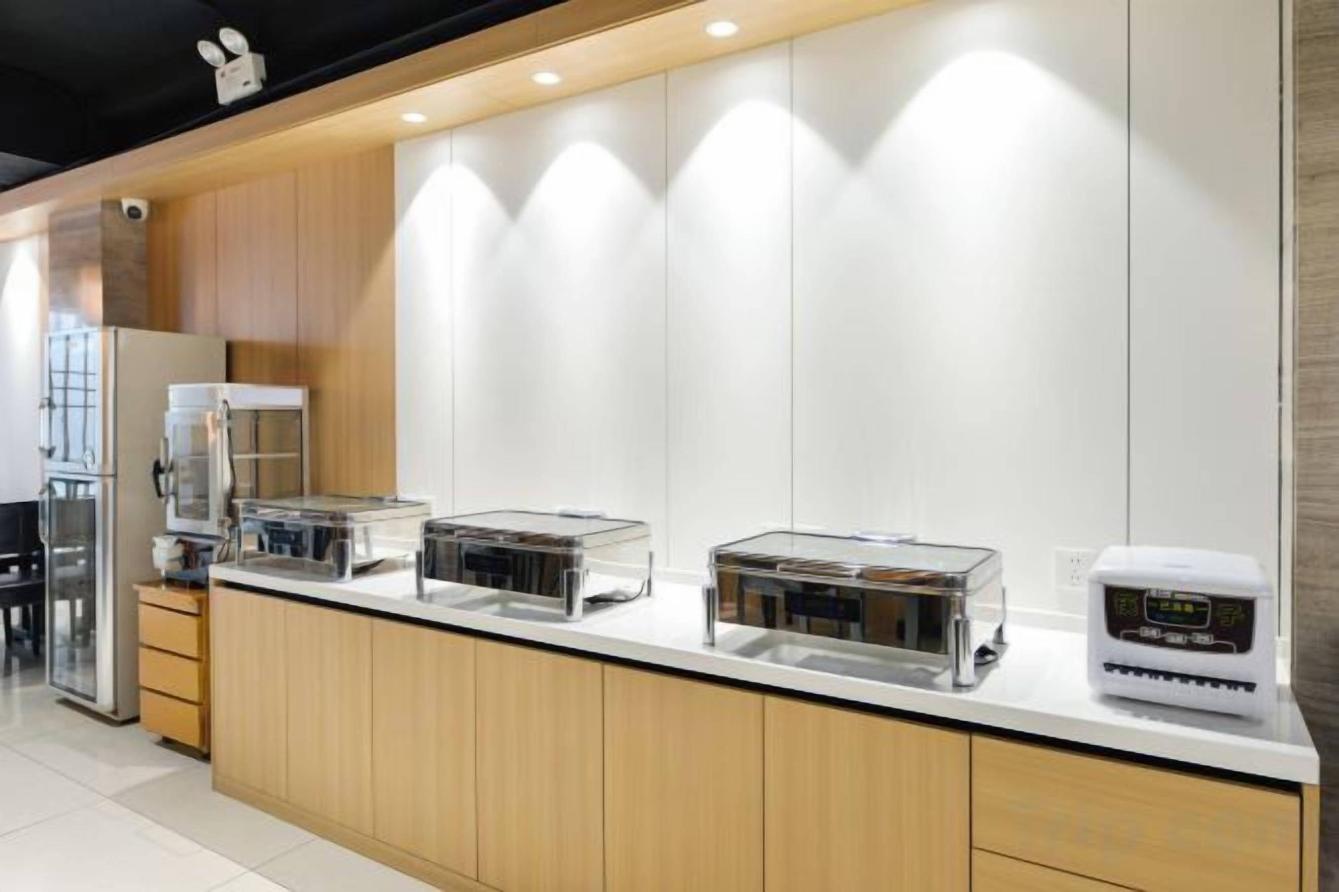 A modern kitchen with a long counter, stainless steel appliances, and wooden cabinets.