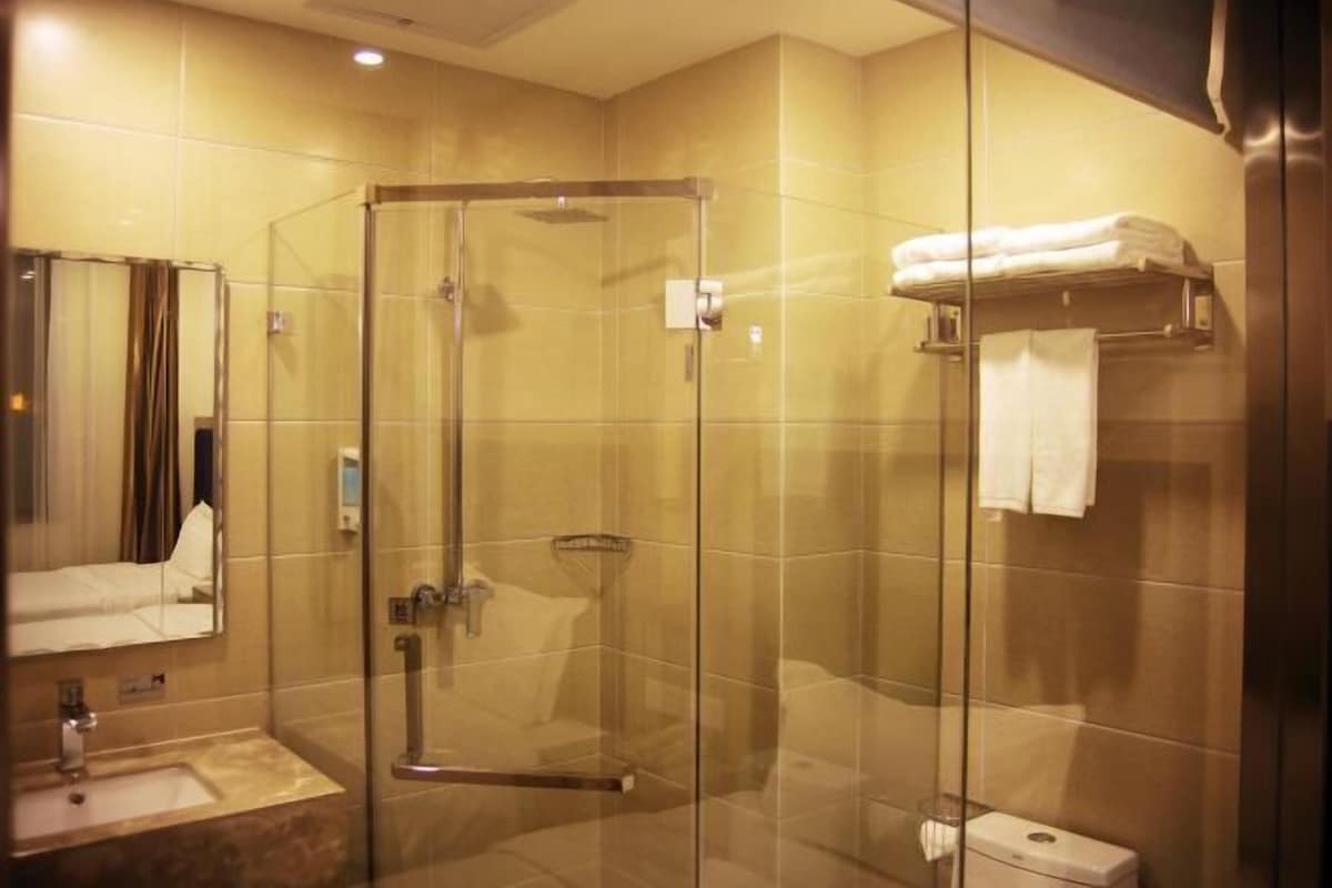 A glass-enclosed shower stall with a sink and mirror, a towel rack, and a toilet.