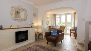 A living room with a fireplace, a dining area with a table and chairs, and a view through an archway to a balcony.
