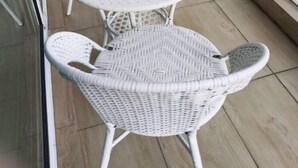 Un balcon agrémenté de meubles en osier blanc, notamment une table ronde et deux chaises.