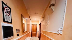 A hallway with a herringbone floor, a white table with chairs, a mounted TV, and a no-smoking sign. - FUNNY HOLIDAY ROME (Rome)