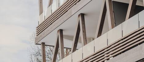 A modern building with a geometric facade featuring triangular wooden frames and horizontal lines.
