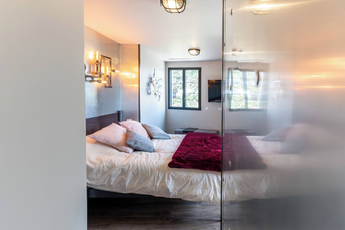 A modern bedroom with a bed, bedside table, and a window.
