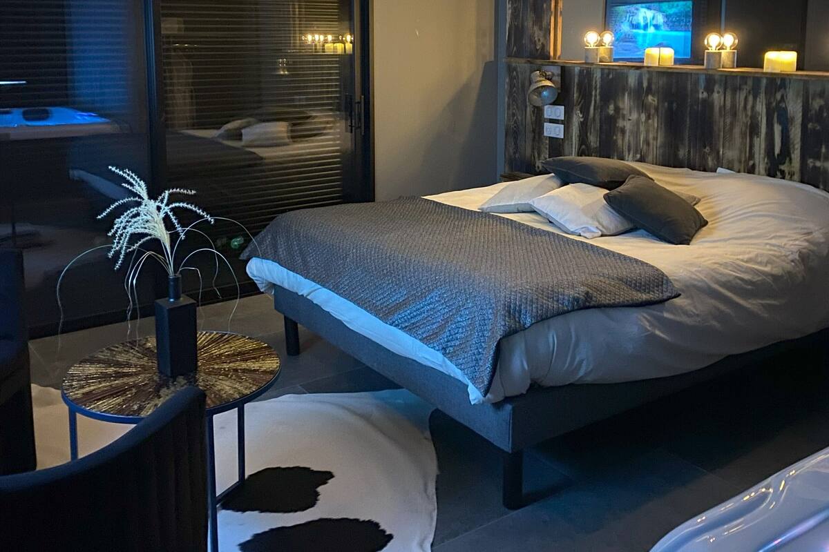 A modern bedroom with a large bed, a mirror, and a ceiling light fixture.