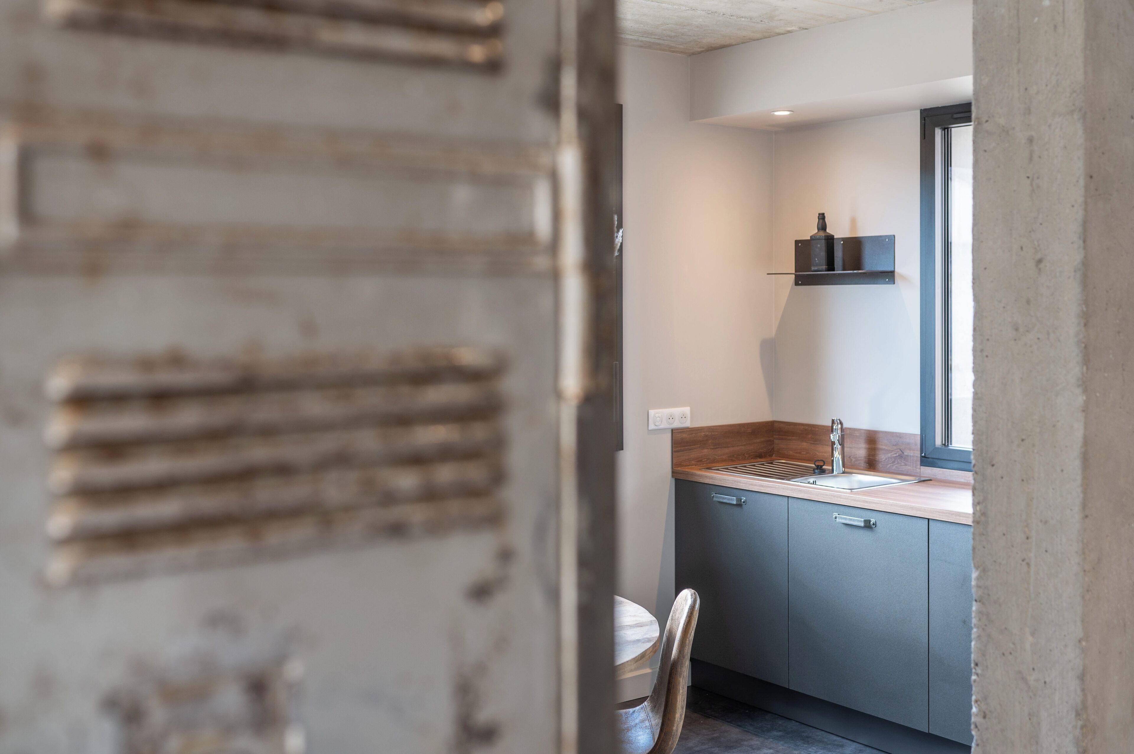 A modern kitchen with grey cabinets, a wooden countertop, and a window above the sink.