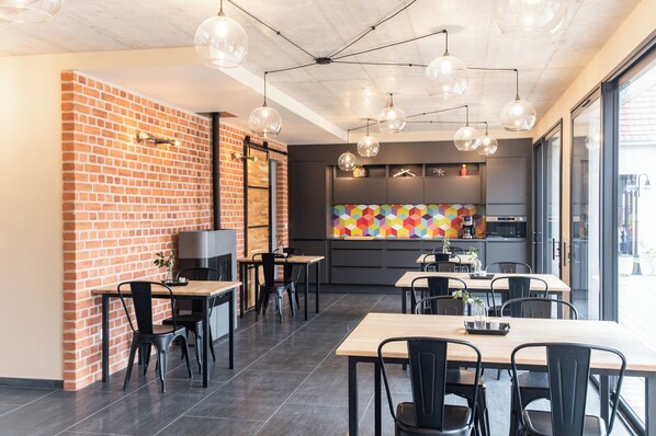 Un restaurante moderno con paredes de ladrillo, sillas negras y un colorido salpicadero geométrico.