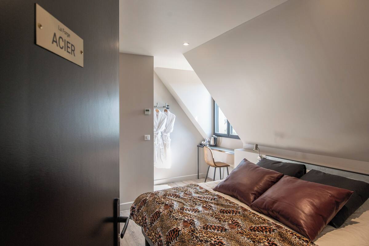A bedroom with a bed, a desk, and a chair. There is a sign on the wall and a window.