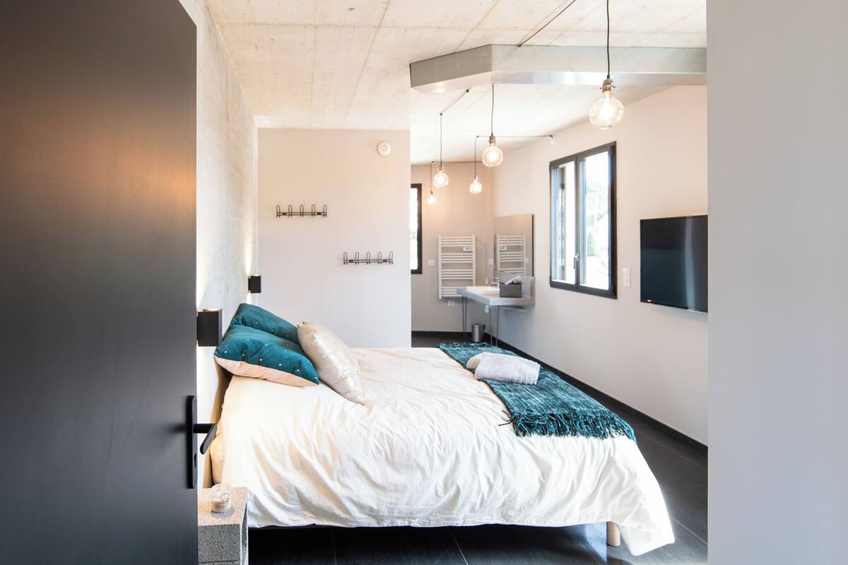 A modern bedroom with a bed, bedside tables, a mirror, and a TV.