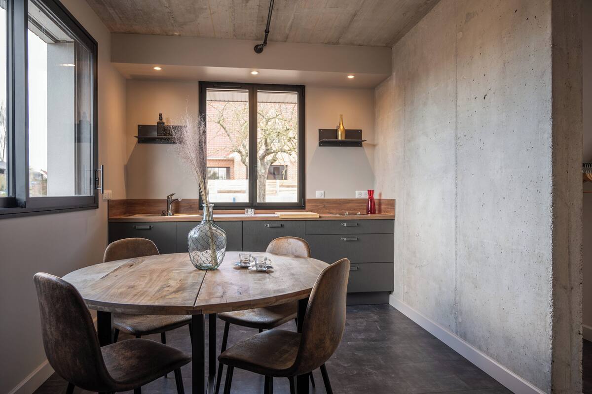 A modern kitchen with a round dining table, chairs, and a vase on the table.