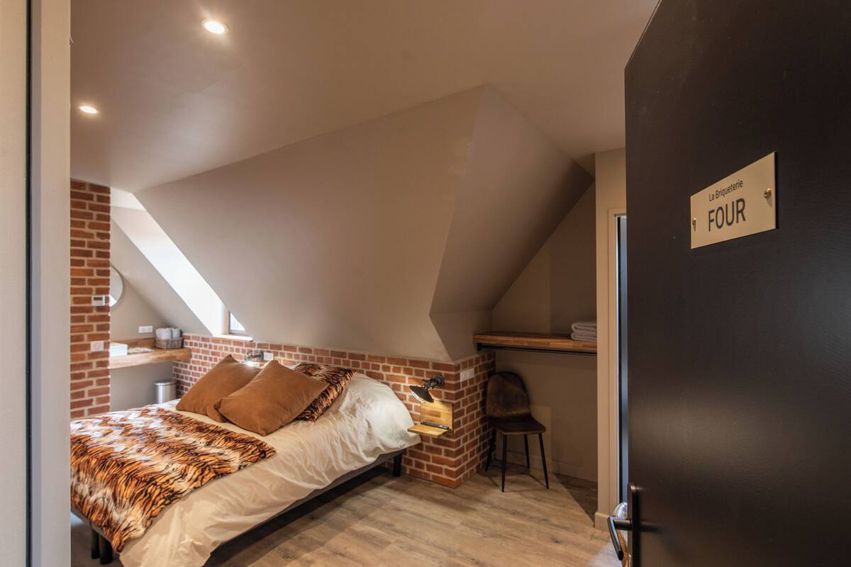 A bedroom with a sloped ceiling, a bed with a tiger print blanket, a desk with a chair, and a sign indicating room number FOUR.