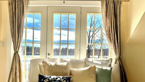 A bed with a 'Welcome to our Lake House' pillow, beige bedding, and curtains. - Charming Grand View/Lake Loft in Brewster with WiFi, AC (Brewster)