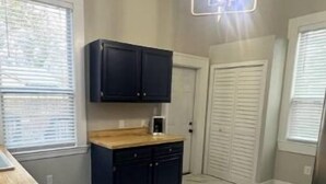 A kitchen with dark cabinets, a wooden countertop, and a modern pendant light. - The Isabella - Beautifully Revived Historic House - 2 blocks from the IP Mill (Bogalusa)