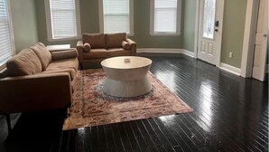 A living room with a sectional sofa, a round coffee table, and a patterned rug. - The Isabella - Beautifully Revived Historic House - 2 blocks from the IP Mill (Bogalusa)