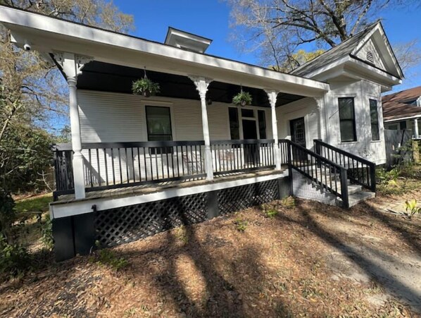 A two-story house with a porch, a staircase, and a small garden area. - The Isabella - Beautifully Revived Historic House - 2 blocks from the IP Mill (Bogalusa)