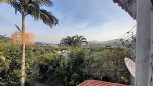 A view from a balcony overlooking a lush landscape with palm trees and dense vegetation. - Casa Jardim Secreto I (Penha)