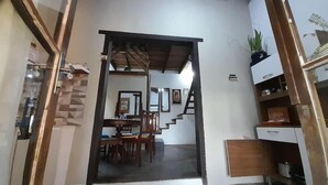 A spacious room with a dining area, a staircase, and a kitchen area. - Casa Jardim Secreto I (Penha)