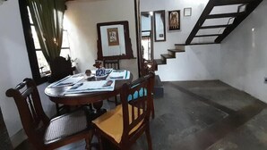 A dining area with a wooden table and chairs, a staircase, and framed pictures on the walls. - Casa Jardim Secreto I (Penha)
