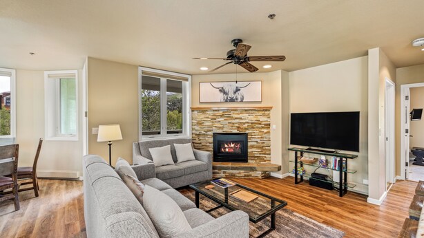 A living room with a fireplace, a television, and a ceiling fan. - Terraces Condo w/ Stunning Views, Pool & Spa 1078 (Steamboat Springs)