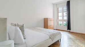 A bedroom with a bed, a wardrobe, and a window with curtains.