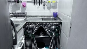 A compact kitchen with a sink, a stove, and a small storage area beneath the counter.