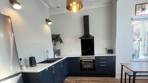 A modern kitchen with a built-in oven, a black stove hood, and a pendant light. - The Cube hidden gem in the heart of ilfracombe , 2 minute walk to tunnels beach! (Ilfracombe)