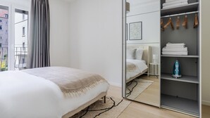 A modern bedroom with a bed, a wardrobe, and a view of the outside.