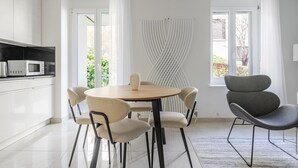 A modern kitchen with white cabinets, a round dining table, and a grey chair.