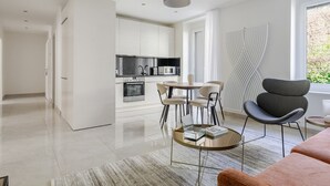 A modern kitchen with white cabinets, a dining area with a round table and chairs, and a large window with curtains.