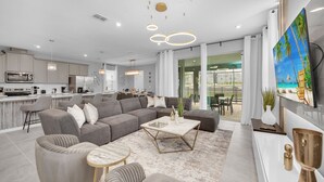 A modern living room with a sectional sofa, a coffee table, and a TV mounted on the wall. - Stunning 6 Bed Pool Home with Game Room-2386SWW (Kissimmee)