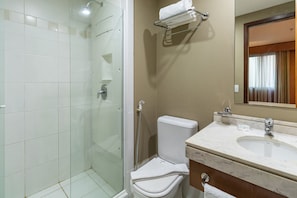 A bathroom with a glass-enclosed shower, a white toilet, and a marble sink.