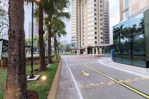 Uma rua urbana moderna com calçada para pedestres, edifícios altos e palmeiras.