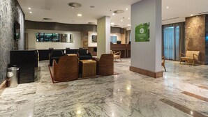 Ένας σύγχρονος χώρος υποδοχής με μαρμάρινο δάπεδο, καθιστικό με ξύλινα καθίσματα, έναν πάγκο υποδοχής και ένα μεγάλο παράθυρο.